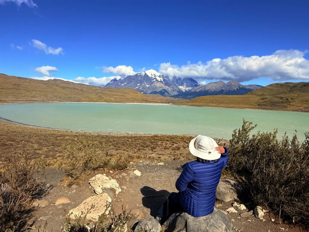Our dear guest enjoying the views at Laguna Amarga, Torres del Paine, while bracing against the wind and holding her hat.