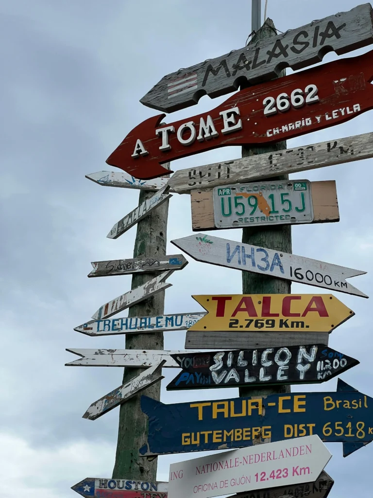 Colorful distance sign in Punta Arenas, showing routes and places across Chile and the world.