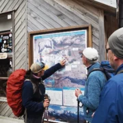 Local guide explaining the W Trek route to two hikers on the trail map at a refugio in Torres del Paine