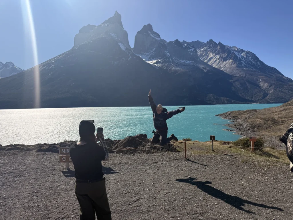 Hiker with open arms at Lake Pehoé, the Cuernos del Paine behind