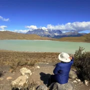 Traveler resting at a viewpoint over a lagoon and the Paine massif, Torres del Paine